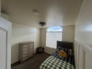 Bedroom with a textured ceiling and dark carpet