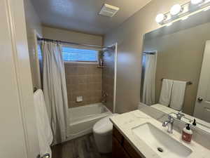 Full bathroom with shower / bath combo, hardwood / wood-style floors, vanity, and toilet