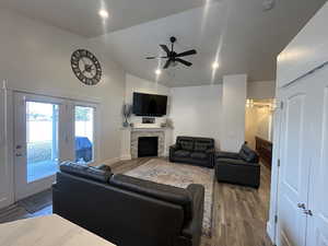 Living room featuring lofted ceiling, hardwood / wood-style floors, a fireplace, and ceiling fan