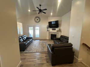 Living room featuring lofted ceiling, hardwood / wood-style flooring, a fireplace, and ceiling fan