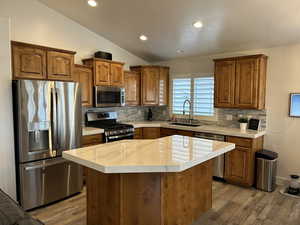 Kitchen featuring sink, a kitchen island, vaulted ceiling, and appliances with stainless steel finishes