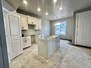 Kitchen with pendant lighting, an inviting chandelier, a center island, a textured ceiling, and white cabinets