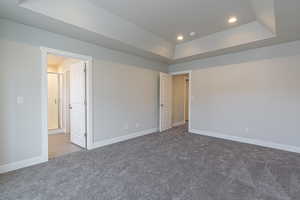 Carpeted empty room with baseboards, a tray ceiling, and recessed lighting
