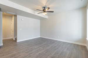 Spare room with baseboards, ceiling fan, dark wood-type flooring, and visible vents
