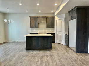 Kitchen featuring hanging light fixtures, a notable chandelier, dark brown cabinetry, and light hardwood / wood-style flooring