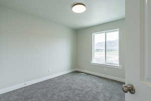 Unfurnished room with baseboards, a mountain view, and dark carpet