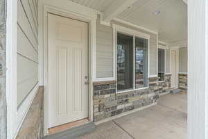 Property entrance featuring covered porch and stone siding