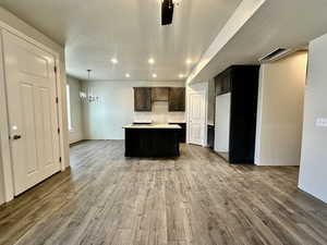 Kitchen featuring wood-type flooring, a textured ceiling, fridge, a kitchen island, and pendant lighting