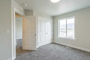 Unfurnished bedroom with carpet flooring, baseboards, visible vents, and a mountain view