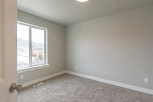 Empty room featuring plenty of natural light, carpet flooring, a mountain view, and visible vents