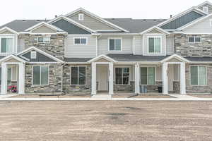 View of property featuring board and batten siding, roof with shingles, and stone siding