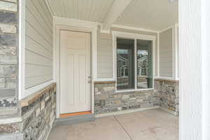 Entrance to property featuring covered porch and stone siding