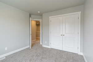 Unfurnished bedroom with visible vents, carpet, and a closet