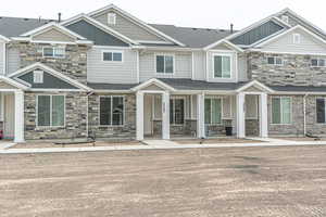 View of property featuring board and batten siding, roof with shingles, covered porch, and stone siding