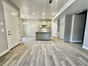 Kitchen featuring an island with sink, sink, pendant lighting, and light hardwood / wood-style flooring