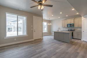 Kitchen with a textured ceiling, wood finished floors, a sink, stainless steel appliances, and recessed lighting