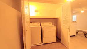 Laundry room with light carpet, ceiling fan, and washing machine and clothes dryer