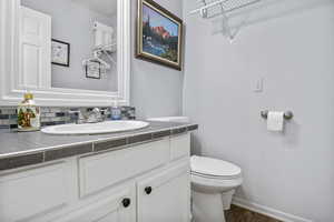 Bathroom featuring tasteful backsplash, vanity, hardwood / wood-style flooring, and toilet