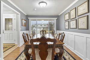 Dining area with ornamental molding, light hardwood / wood-style floors, and a textured ceiling