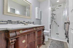 Bathroom with hardwood / wood-style floors, an enclosed shower, vanity, decorative backsplash, and toilet