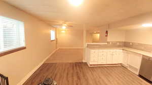 Kitchen with ceiling fan, stainless steel dishwasher, light wood-type flooring, and white cabinets