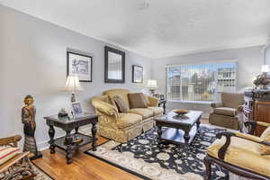 Living room featuring crown molding, wood-type flooring, and a textured ceiling