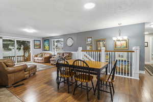 Dining space with hardwood / wood-style flooring, plenty of natural light, a textured ceiling, and a chandelier