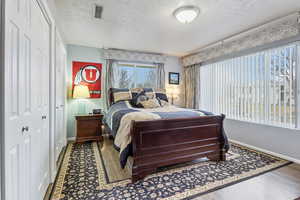 Bedroom featuring a closet, wood-type flooring, and a textured ceiling