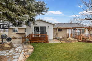 Rear view of property with a yard, a deck, and a patio area