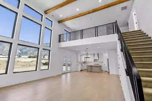 Unfurnished living room featuring a towering ceiling, beamed ceiling, light hardwood / wood-style floors, french doors, and a chandelier