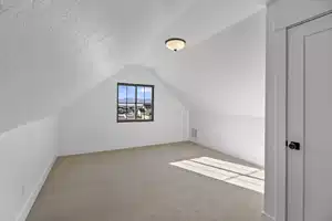 Additional living space featuring vaulted ceiling, carpet, and a textured ceiling