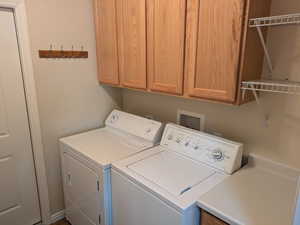 Laundry room with separate washer and dryer and cabinets