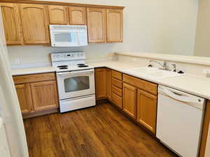 Kitchen with sink, white appliances, and mid-color hardwood / wood-style floors