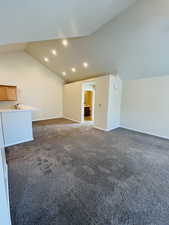 Unfurnished living room with lofted ceiling and mid-color carpet