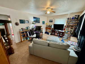 Living room with light carpet, ceiling fan, and a textured ceiling