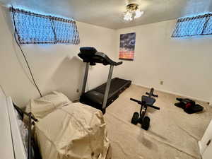 Exercise room with carpet floors and a textured ceiling