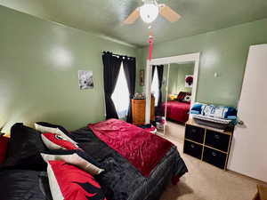 Carpeted bedroom with a textured ceiling, a closet, and ceiling fan