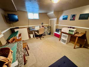 Carpeted home office featuring a textured ceiling