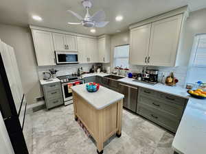 Kitchen featuring sink, white cabinetry, gray cabinets, a kitchen island, and stainless steel appliances