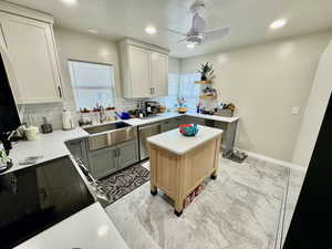 Kitchen featuring sink, dishwasher, gray cabinetry, a healthy amount of sunlight, and a kitchen island