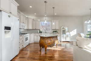 Kitchen featuring pendant lighting, white appliances, tasteful backsplash, and white cabinets