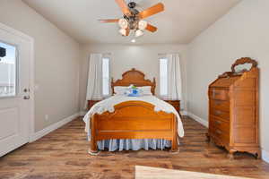 Bedroom featuring ceiling fan, dark hardwood / wood-style floors, and multiple windows