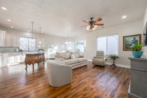 Living room with dark hardwood / wood-style flooring, sink, and ceiling fan with notable chandelier