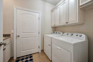 Laundry area with washer and clothes dryer and cabinets