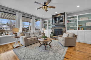 Living room with 13' ceilings, built in shelves, a stone fireplace, expansive windows and hardwood flooring