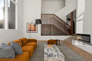 Living room with hardwood / wood-style flooring and a towering ceiling