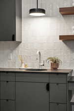 Kitchen with tasteful backsplash, sink, gray cabinetry, and tile walls