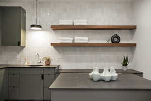 Kitchen with pendant lighting, sink, backsplash, and gray cabinets