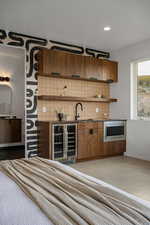 Kitchen with stainless steel microwave, backsplash, sink, and beverage cooler