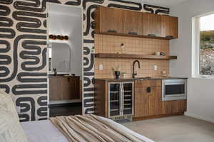 Bar featuring wine cooler, stainless steel microwave, sink, and tasteful backsplash